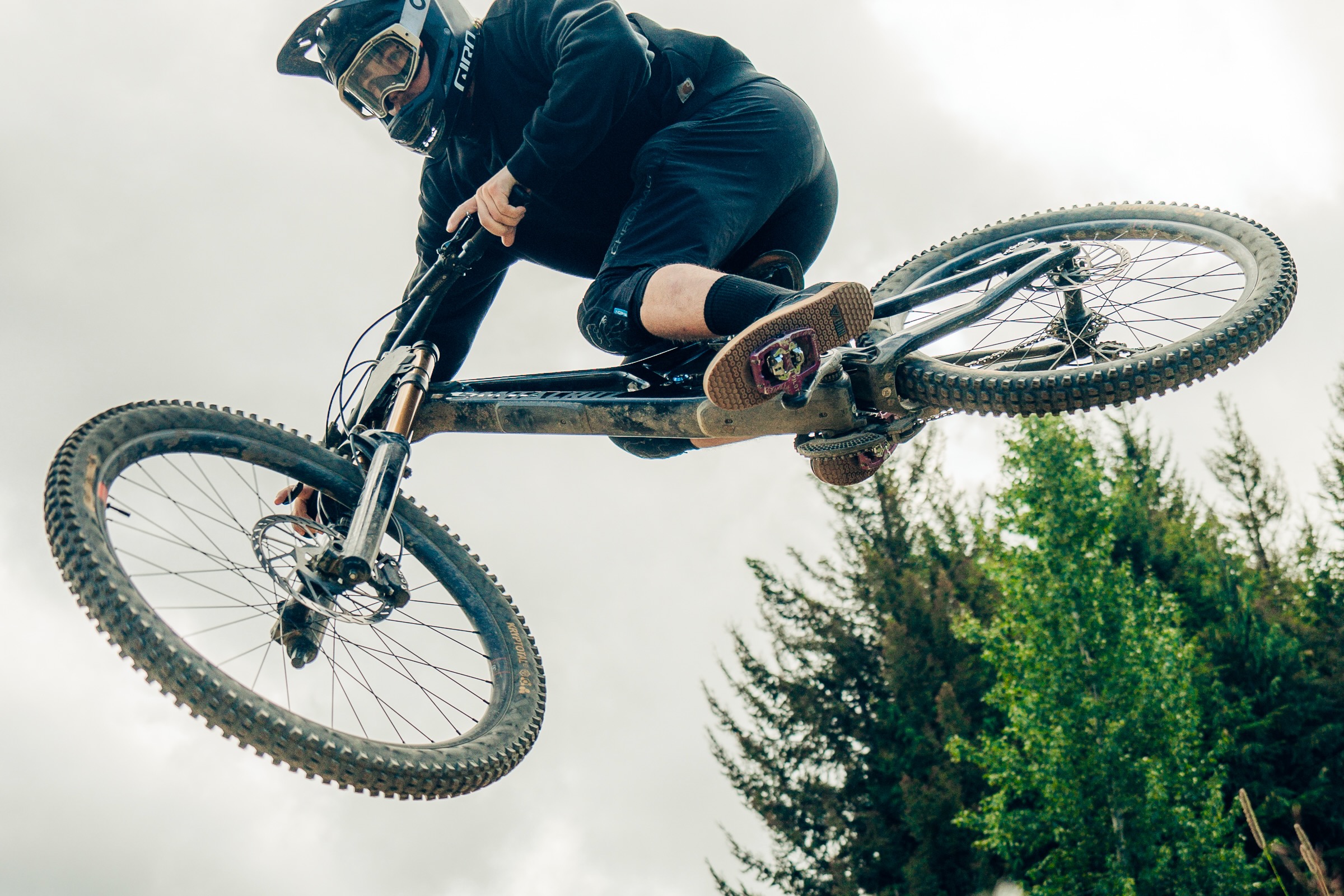 a mountain biker jumping on a downhill bike wearing the Drift Minna shoes