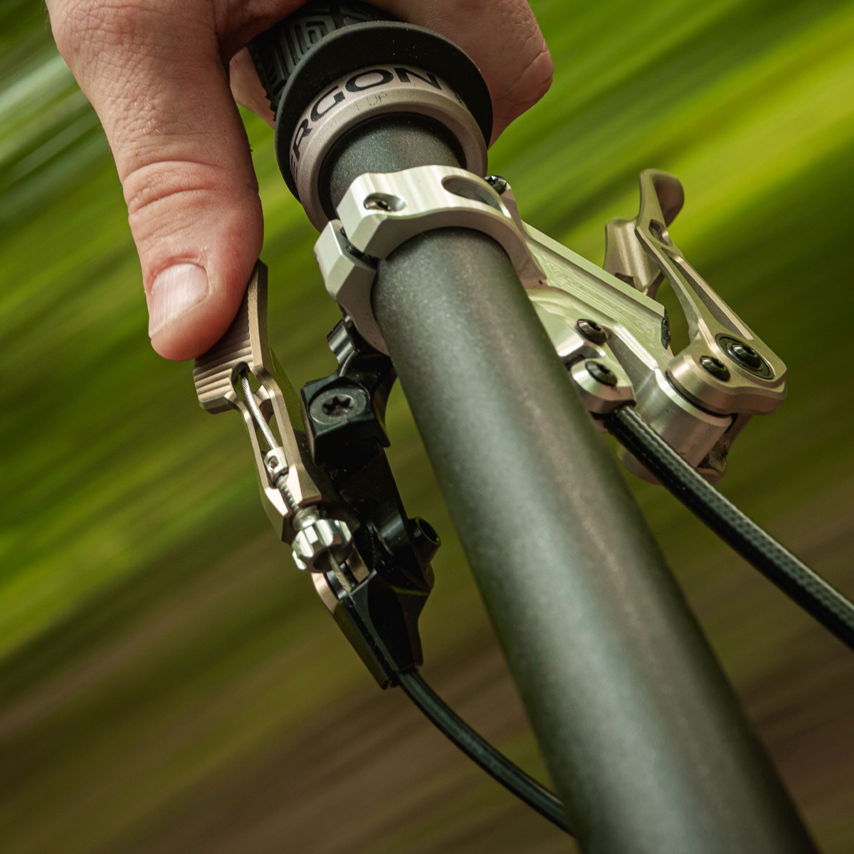 The Intend Elevator Boy dropper remote mounted on the handlebar of a mountain bike and being pushed by a thumb.