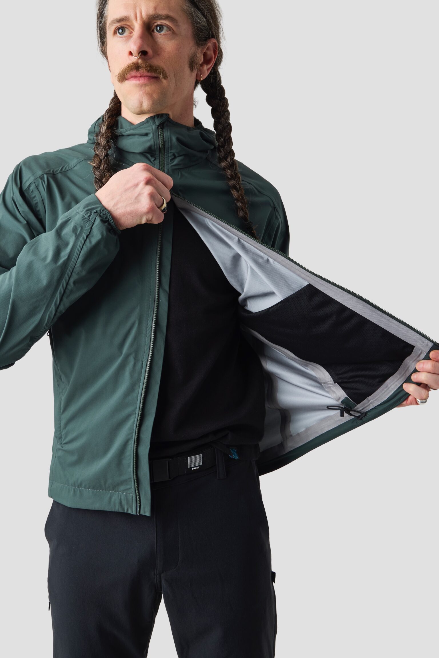 studio image of a man wearing the Ornot Fog eater Hooded Rain Jacket using the 2-way zipper