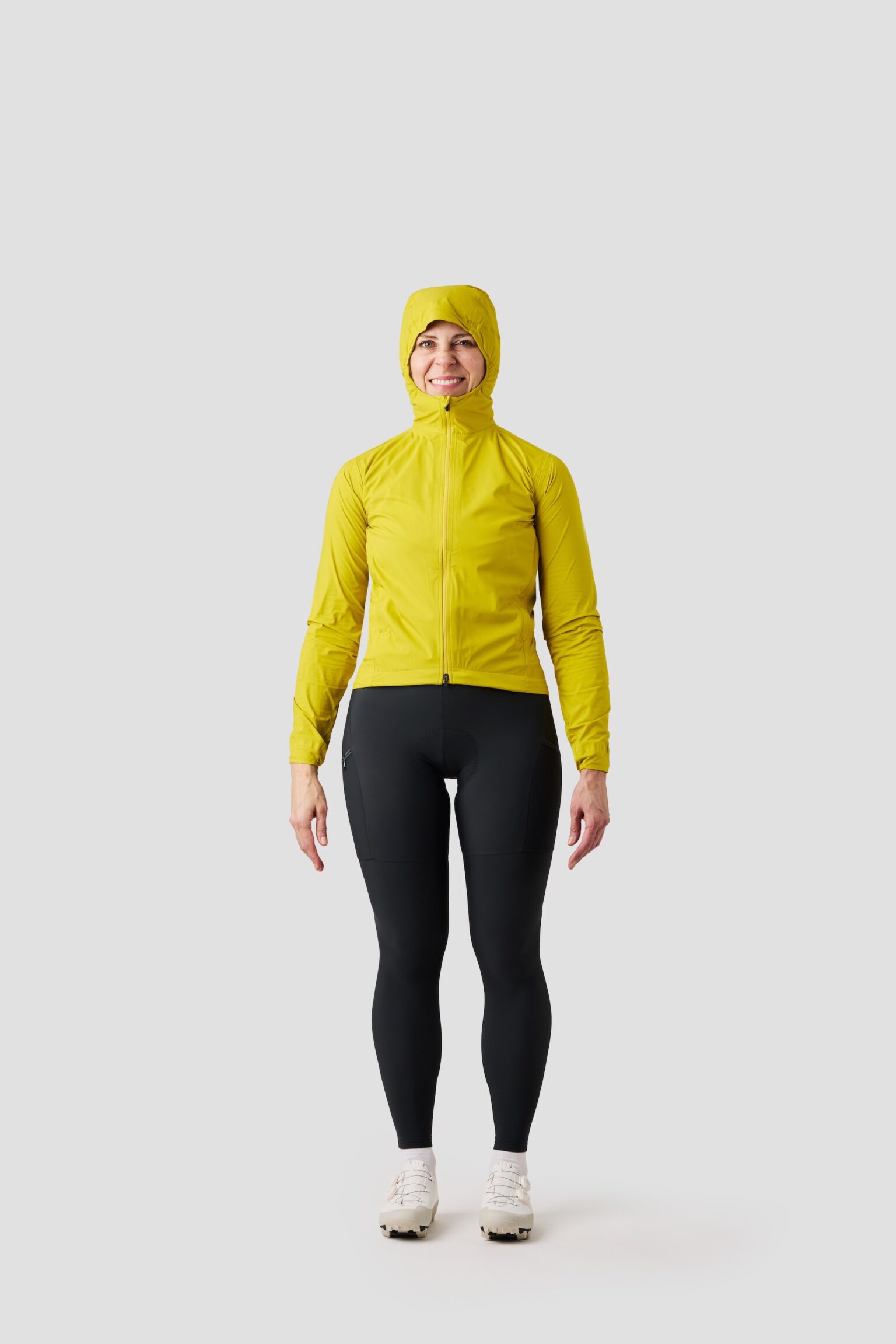 studio image of a woman wearing the Ornot Fog eater Hooded Rain Jacket