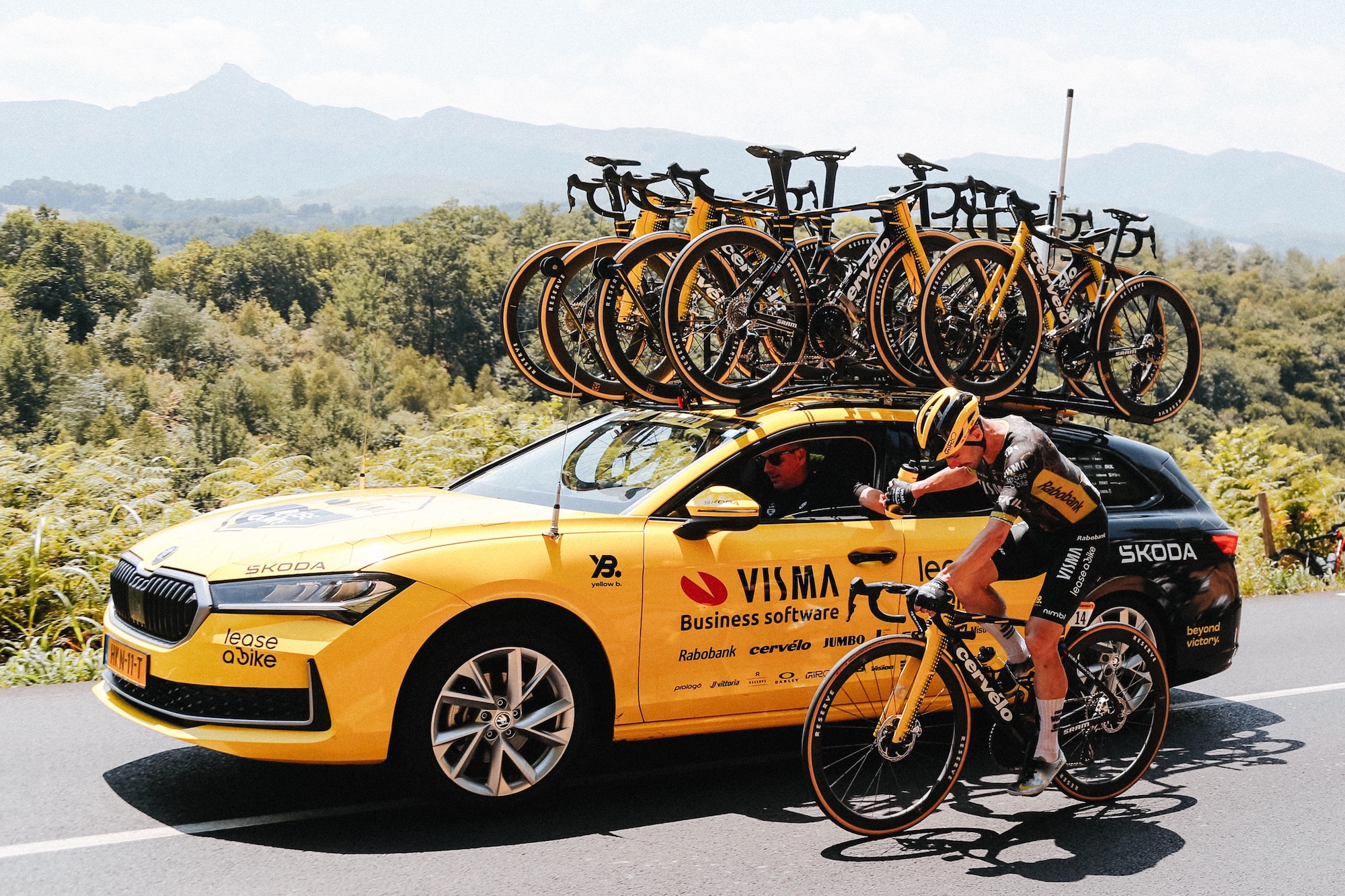 a Visma rider taking water bottles from the team car.