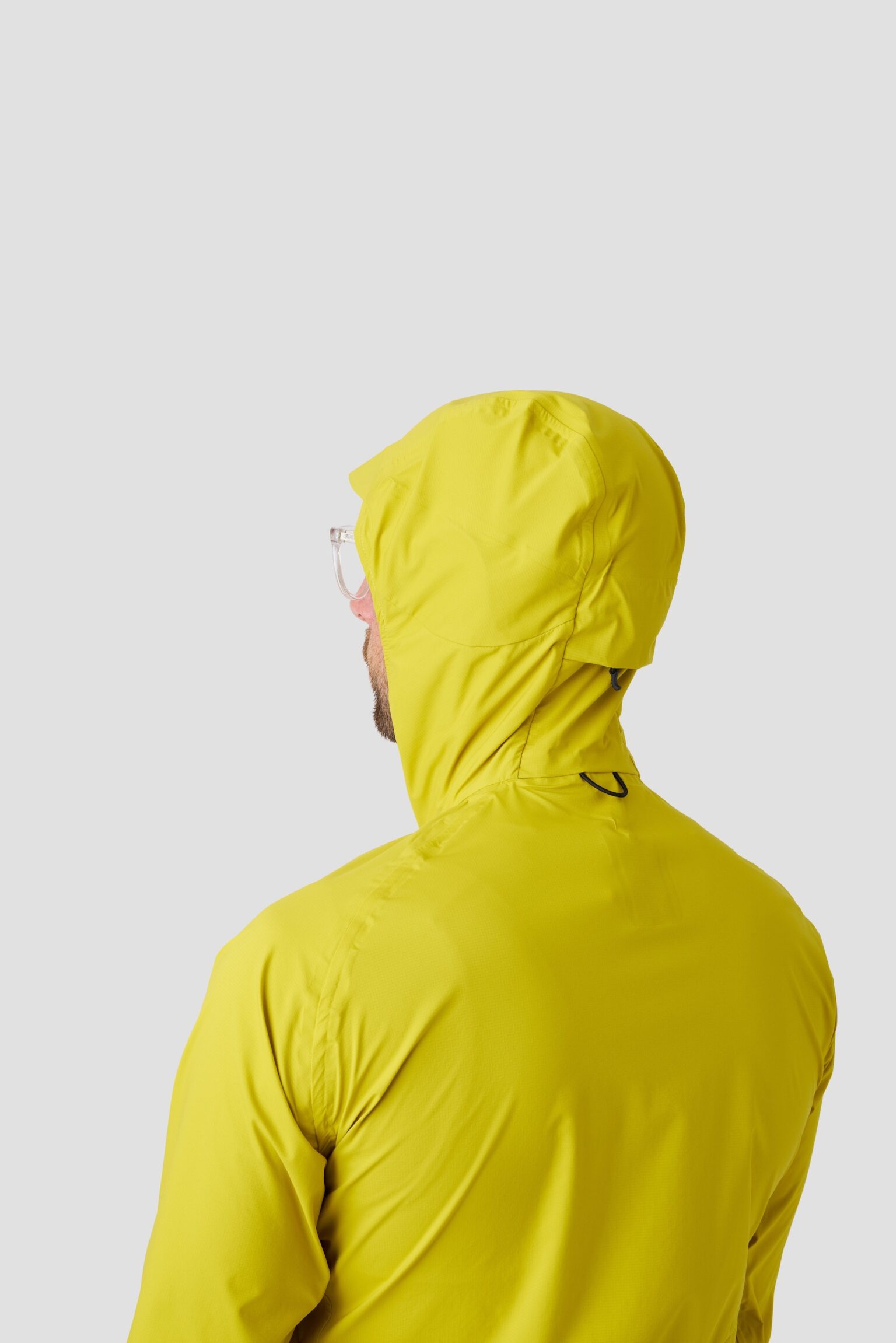 studio image of a man wearing the Ornot Fog eater Hooded Rain Jacket with the hood up