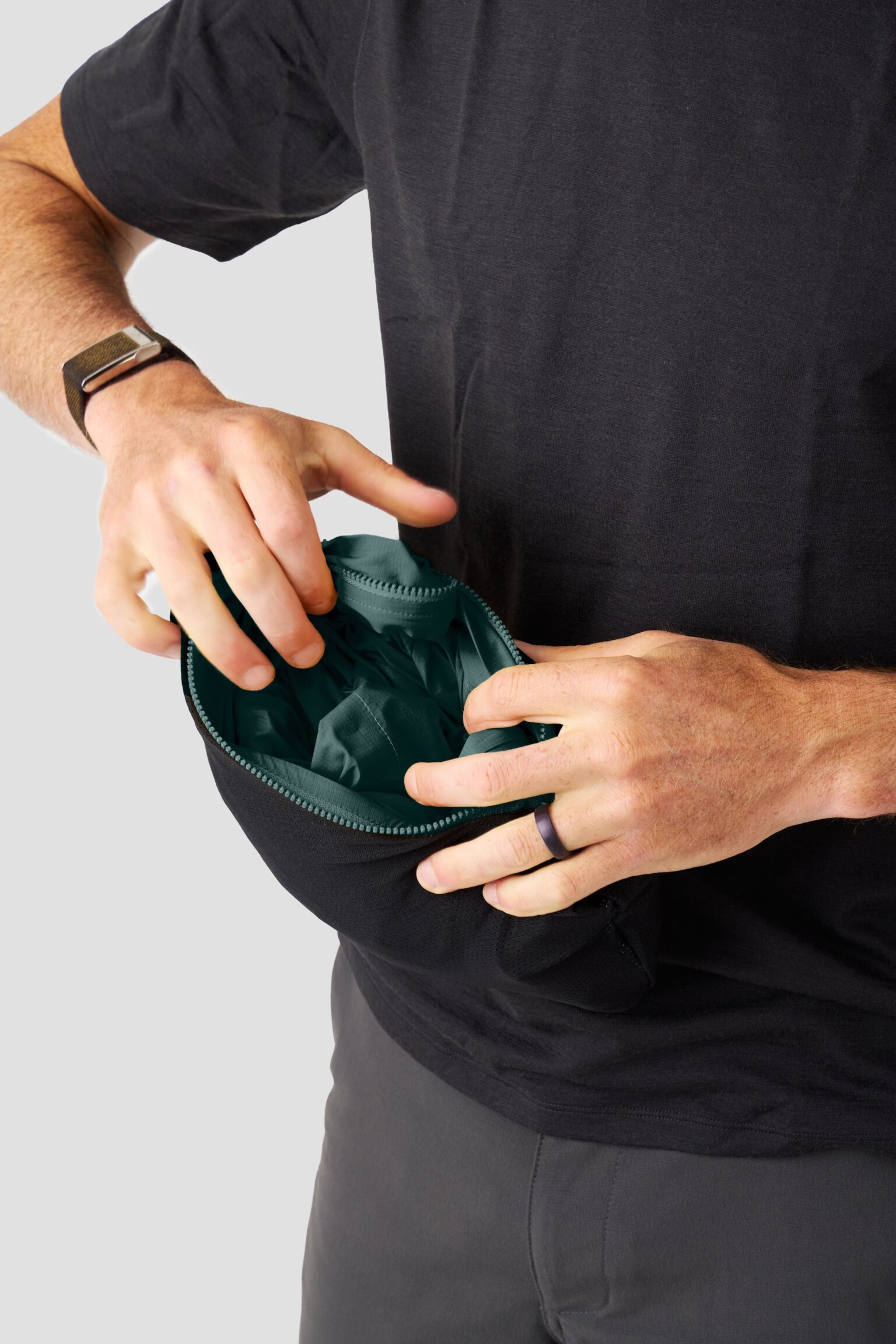 studio image of a man packing the Ornot Fog Eater into its own pocket